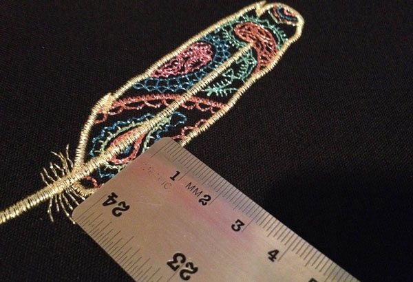 Pull Distortion And Pull Compensation | Machine Embroidery Measuring an embroidered feather made of metallic thread with a metric ruler.
